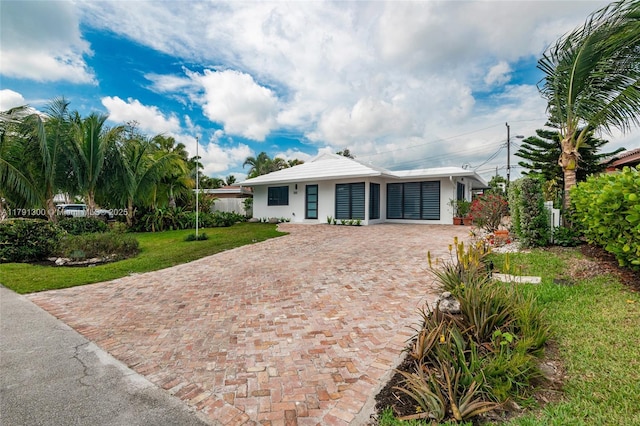 ranch-style home with stucco siding, a front yard, and driveway
