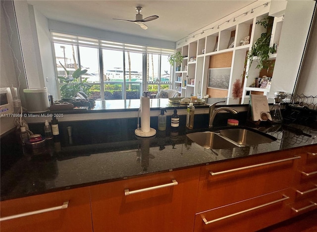 kitchen with dark stone countertops, open shelves, ceiling fan, and a sink
