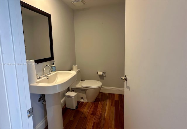 bathroom with toilet, visible vents, wood finished floors, and baseboards