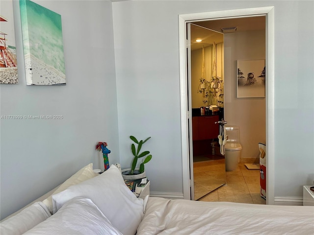 bedroom featuring baseboards, visible vents, ensuite bath, and tile patterned flooring