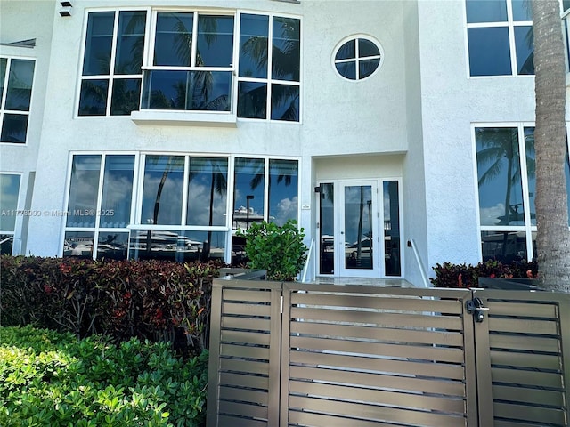 doorway to property featuring a gate, fence, and stucco siding