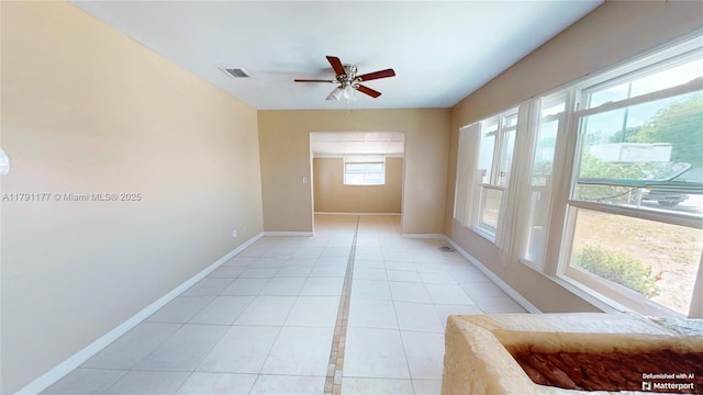 empty room featuring light tile patterned floors, ceiling fan, visible vents, and baseboards