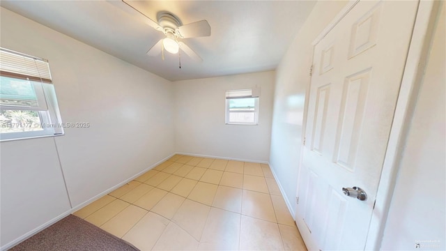spare room featuring light tile patterned flooring, a ceiling fan, and baseboards