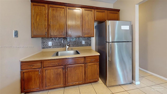 kitchen with tasteful backsplash, a sink, light countertops, and freestanding refrigerator
