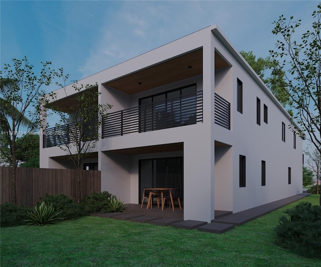back of house featuring a patio area, a balcony, a lawn, stucco siding, and fence