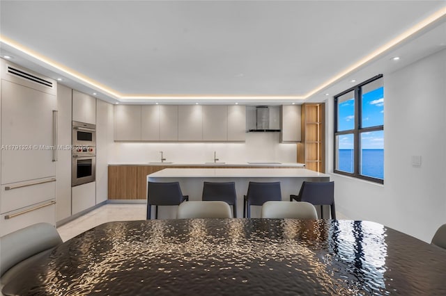 9801 Collins Ave Unit 17R, Bal Harbour, FL 33154 - kitchen with wall chimney range hood, a kitchen breakfast bar, a sink, and modern cabinets
