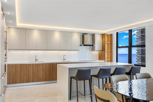 9801 Collins Ave Unit 17R, Bal Harbour, FL 33154 - kitchen featuring wall chimney range hood, a sink, a breakfast bar area, a kitchen island, and modern cabinets