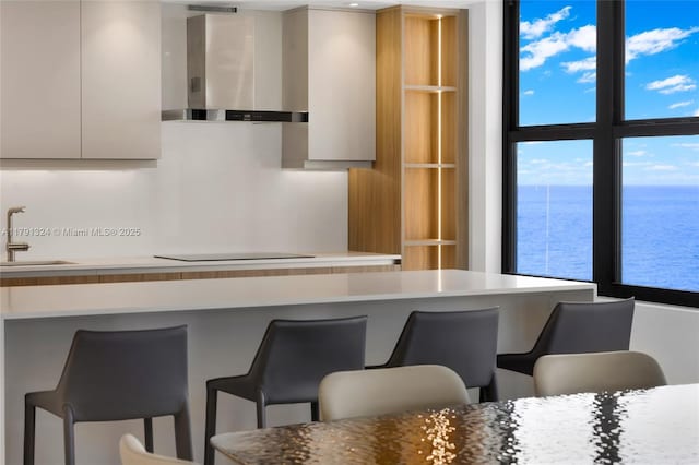 9801 Collins Ave Unit 17R, Bal Harbour, FL 33154 - kitchen with wall chimney range hood, black electric stovetop, a sink, and modern cabinets