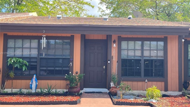 doorway to property with board and batten siding and roof with shingles