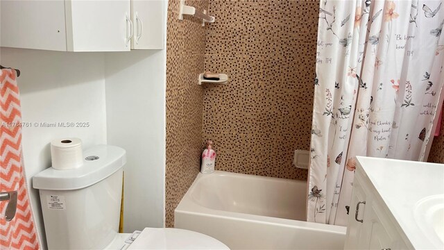 bathroom with shower / bath combo with shower curtain, toilet, and vanity