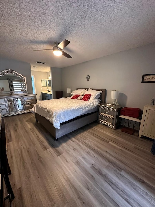 13686 SW 116th Ln, Miami, FL 33186 - bedroom with a textured ceiling, connected bathroom, visible vents, wood finished floors, and a ceiling fan