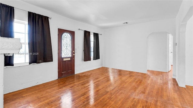 entrance foyer featuring arched walkways, visible vents, and wood finished floors