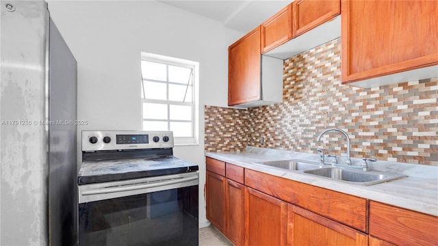 kitchen with appliances with stainless steel finishes, decorative backsplash, light countertops, and a sink