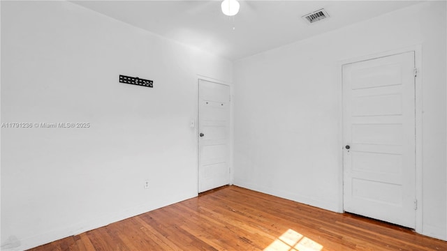 spare room featuring baseboards, visible vents, a ceiling fan, and light wood-style flooring