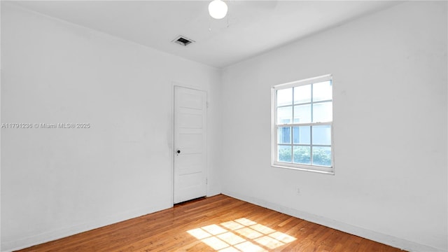 spare room featuring baseboards, visible vents, a ceiling fan, and light wood finished floors
