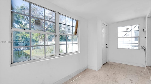 empty room featuring baseboards and plenty of natural light
