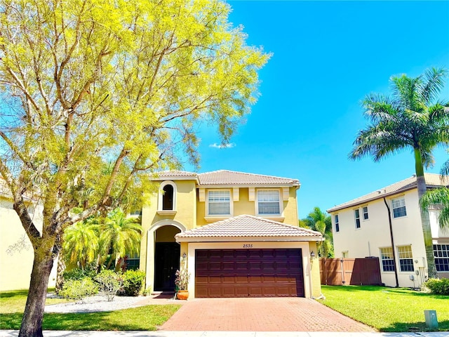 view of front of house with fence, a tile roof, a garage, stucco siding, and decorative driveway