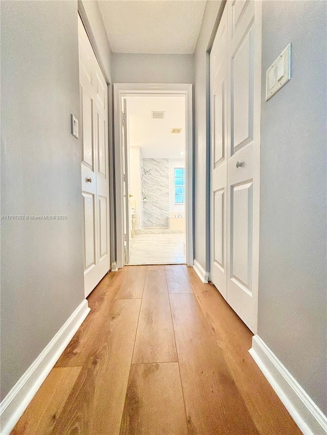 hall with baseboards and light wood-style flooring