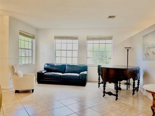 living area featuring baseboards, visible vents, and light tile patterned floors