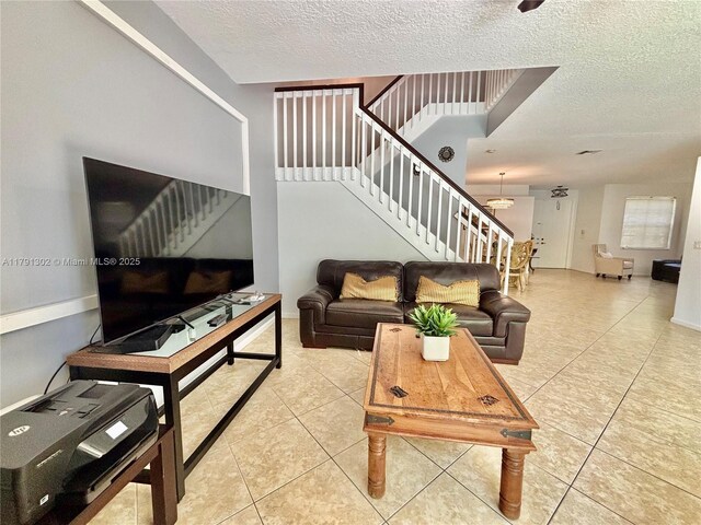 living room featuring tile patterned flooring, stairs, and a textured ceiling