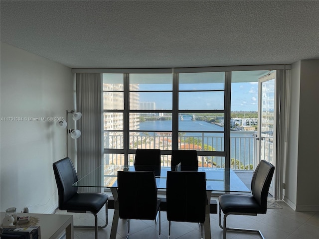 301 174th St Unit 1105, Sunny Isles Beach, FL 33160 - dining space featuring a water view, a textured ceiling, a wall of windows, light tile patterned floors, and baseboards