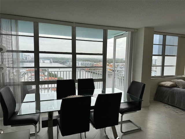 dining room featuring light tile patterned floors, a water view, a textured ceiling, and floor to ceiling windows