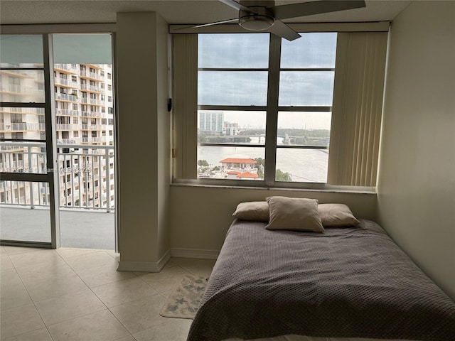 bedroom with tile patterned flooring, access to outside, floor to ceiling windows, and baseboards