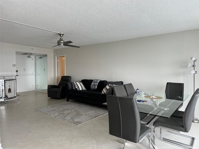 interior space with ceiling fan, a textured ceiling, and light tile patterned flooring