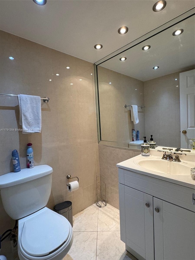 bathroom with toilet, recessed lighting, tile walls, and vanity