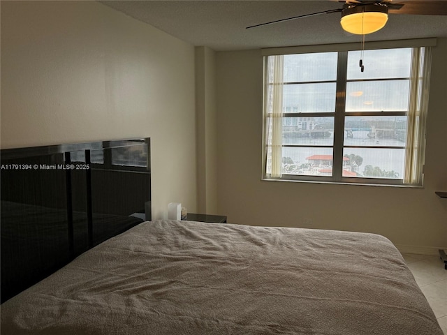 tiled bedroom featuring baseboards, a ceiling fan, and multiple windows
