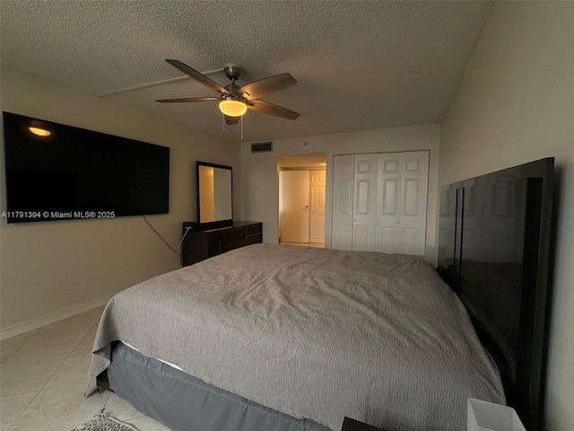 tiled bedroom with visible vents, ceiling fan, a textured ceiling, and a closet