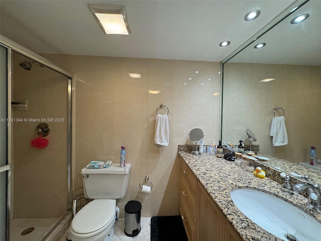 bathroom featuring recessed lighting, tile walls, a shower stall, vanity, and toilet