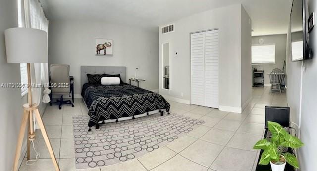 bedroom featuring a closet, visible vents, tile patterned floors, and baseboards