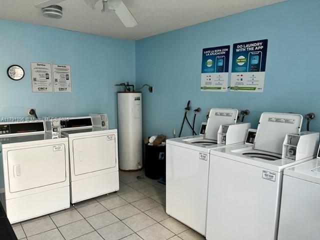 shared laundry area featuring light tile patterned floors, ceiling fan, water heater, and independent washer and dryer