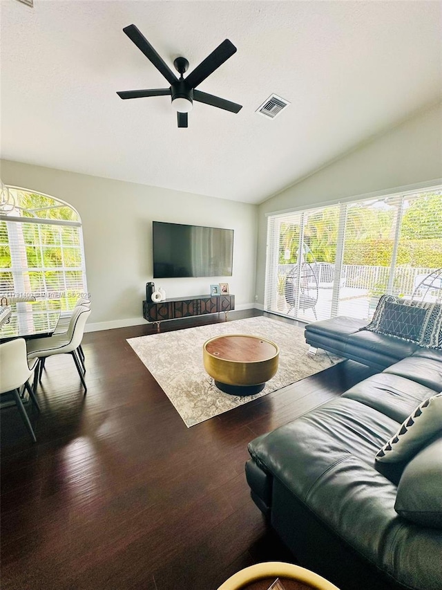 living area featuring a healthy amount of sunlight, vaulted ceiling, baseboards, visible vents, and a ceiling fan