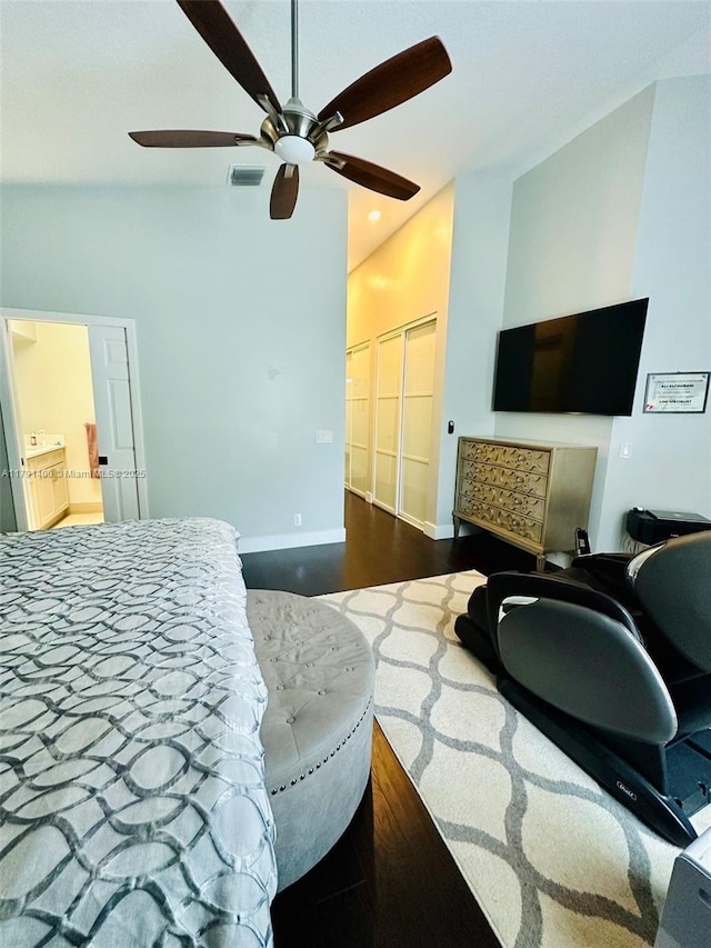 bedroom featuring connected bathroom, visible vents, baseboards, dark wood-type flooring, and a ceiling fan