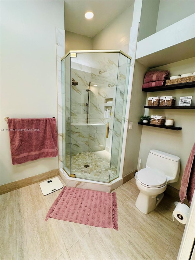 full bath with baseboards, wood finished floors, a marble finish shower, and toilet