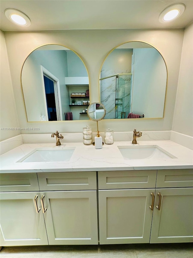 full bath with a shower stall, double vanity, and a sink