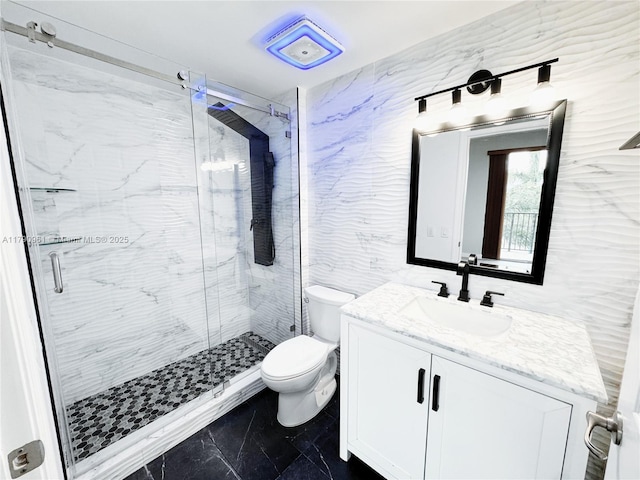 bathroom with vanity, toilet, marble finish floor, and a marble finish shower