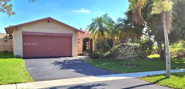 view of front of house featuring a front yard, driveway, an attached garage, and brick siding