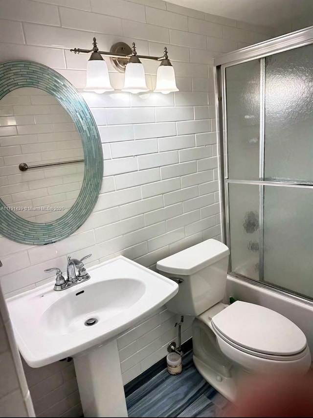 2150 Sans Souci Blvd Unit B611, North Miami, FL 33180 - bathroom with tile walls, toilet, and bath / shower combo with glass door
