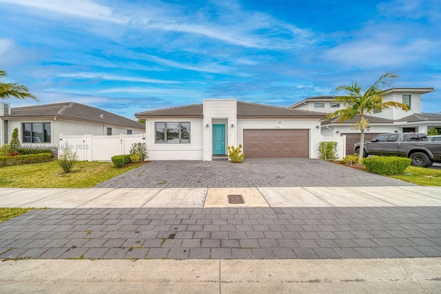 view of front of property with an attached garage, decorative driveway, fence, and stucco siding