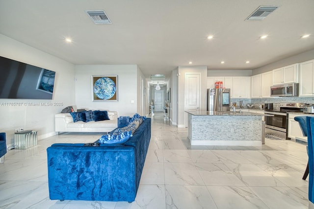 living area featuring baseboards, visible vents, and marble finish floor