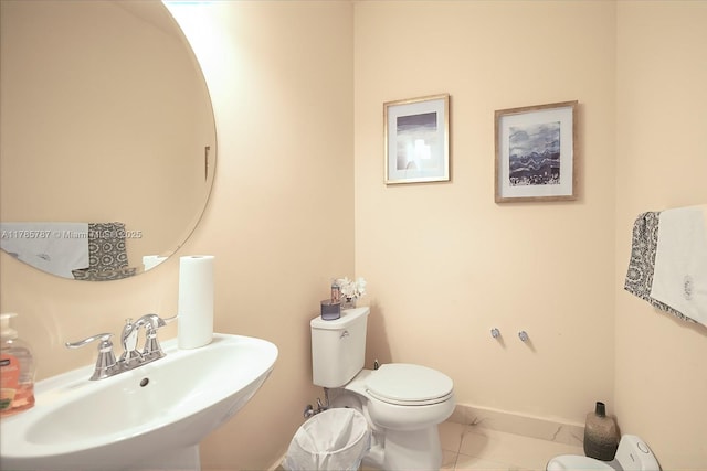 half bathroom featuring baseboards, a sink, and toilet