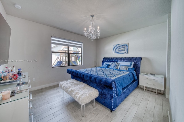 bedroom featuring baseboards, a notable chandelier, and light wood finished floors
