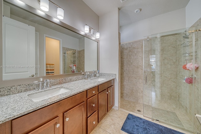 full bathroom with double vanity, a shower stall, a sink, and tile patterned flooring