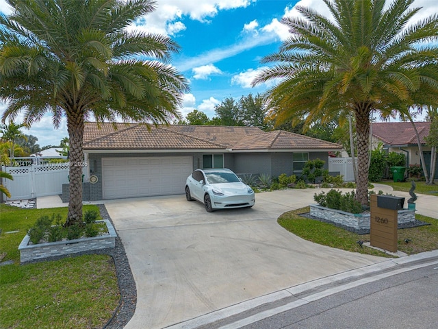 ranch-style home featuring concrete driveway, a garage, a tiled roof, and fence