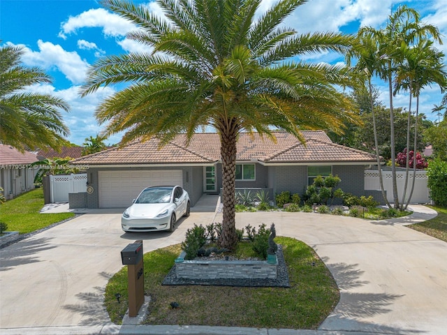 view of front of home featuring fence, a garage, a tiled roof, and curved driveway