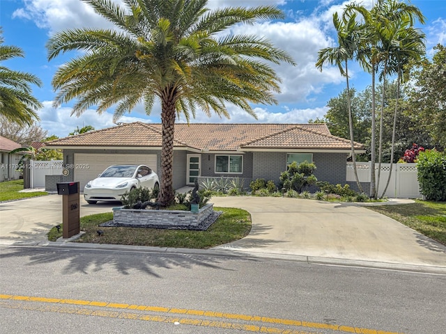 ranch-style home with a garage, a tiled roof, brick siding, concrete driveway, and fence
