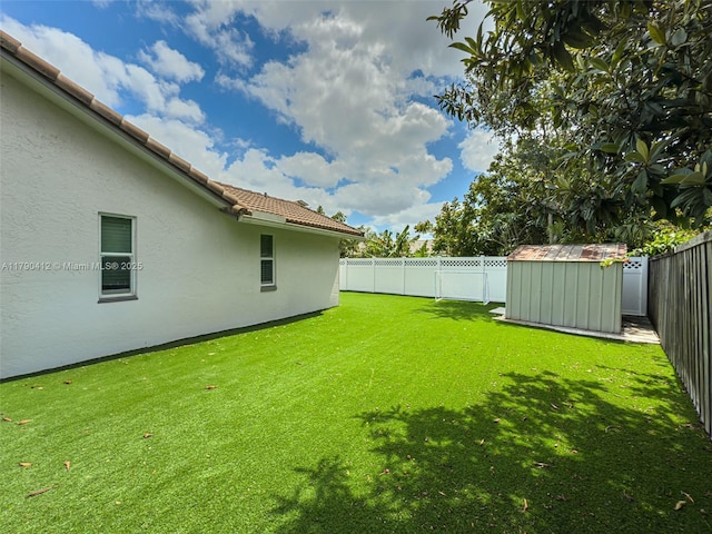 view of yard featuring a storage unit, a fenced backyard, and an outbuilding